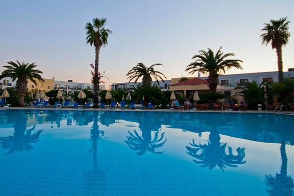 Ein Swimmingpool im Tigaki Beach Hotel mit blauem Wasser und reflektierenden Palmen.