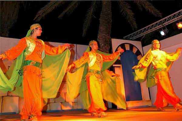 Drei Tänzer im orientalischen Gewand auf der Bühne des El Mouradi Skanes bei Nacht.