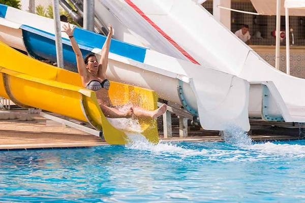 Frau rutscht auf einer gelben Wasserrutsche im El Mouradi Skanes Hotel
