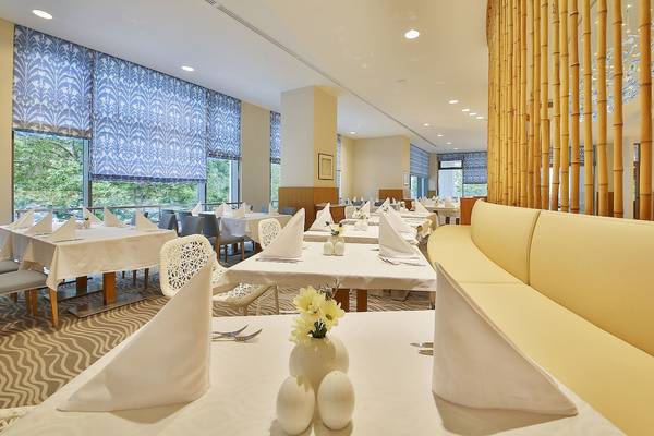 Innenansicht des Restaurants im Maritim Hotel Paradise Blue Albena mit gedeckten Tischen und Stühlen.