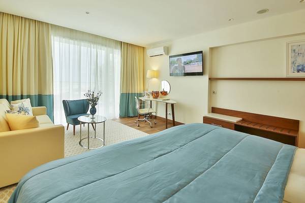 Innenansicht des Maritim Hotel Paradise Blue Albena Zimmers mit Bett, Schreibtisch und Fernseher.