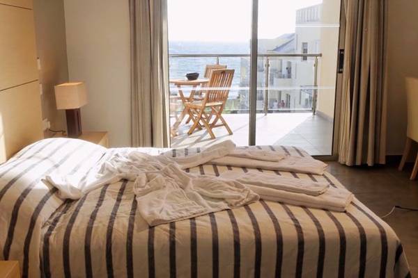 Schlafzimmer mit Meerblick im Capital Coast Resort & Spa, Bett mit weißen Handtüchern und Blick auf einen Balkon mit Tisch und Stühlen.