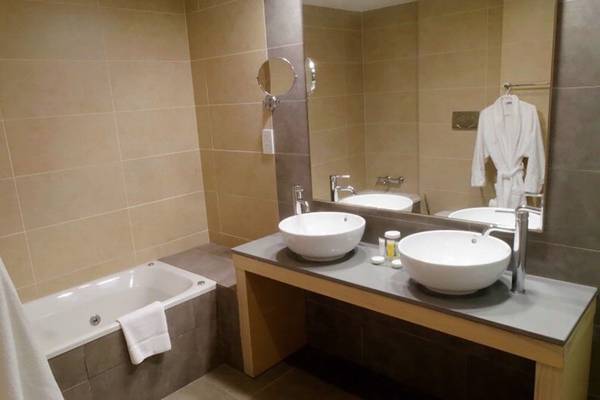 Badezimmer im Capital Coast Resort & Spa mit Badewanne, Waschbecken und Spiegel