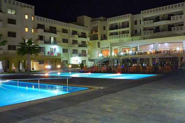 Nachtansicht des Capital Coast Resort & Spa mit zwei beleuchteten Swimmingpools und einer Hotelbar.