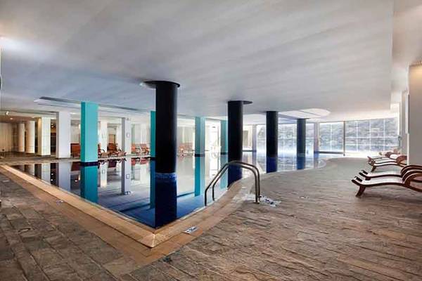 Innenpool im Capital Coast Resort & Spa mit Lounge-Liegen und blauen Säulen.