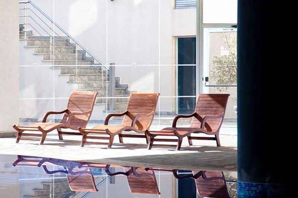 Drei Holzloungestühle vor dem Capital Coast Resort & Spa neben einem Swimmingpool