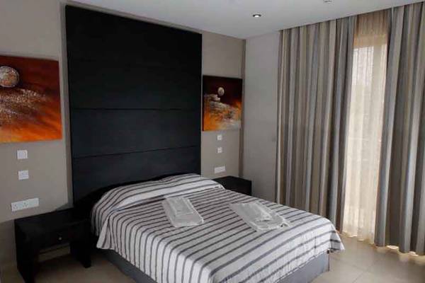 Schlafzimmer im Capital Coast Resort & Spa mit Doppelbett, Kunstwerken und offenen Vorhängen.