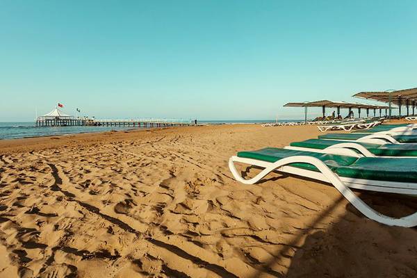 Strand des Turan Prince Hotels mit Sonnenliegen und Pier am Horizont