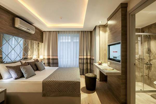 Schlafzimmer im Turan Prince Hotel mit Doppelbett, Fernseher und Dusche.
