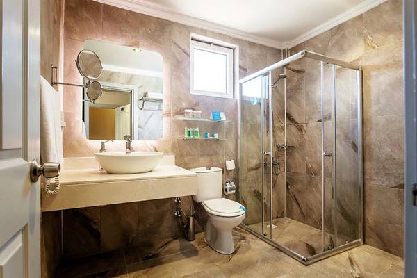 Badezimmer im Turan Prince Hotel mit Waschbecken, Spiegel, Toilette und Glasdusche.