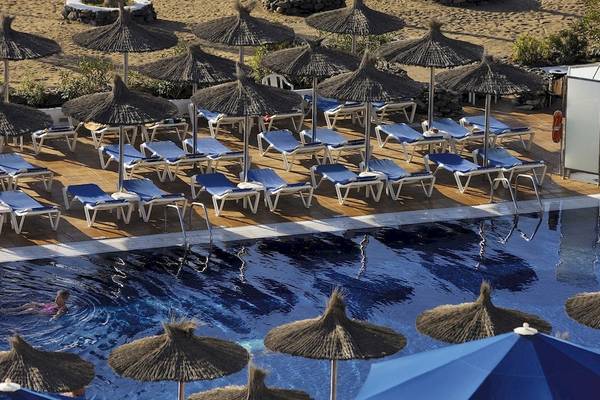 Poolbereich des VIK Hotels San Antonio mit vielen Liegestühlen und Sonnenschirmen.