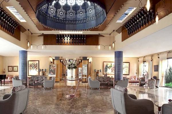 Lobby des Le Meridien N'Fis Hotels mit großen Kronleuchtern, Sofas und einem Klavier.