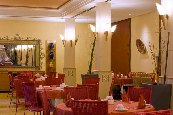 Innenbereich des Restaurants im Le Meridien N'Fis Hotel mit runden Tischen und Stühlen, Tischdecken und Kerzen.