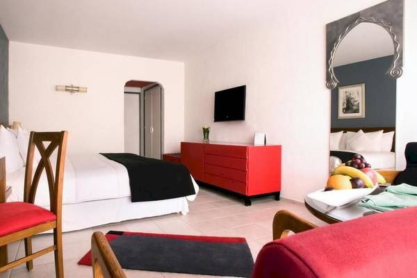 Innenansicht eines Hotelzimmers im Le Meridien N'Fis, mit Bett, rotem Schrank und Früchten auf dem Tisch.