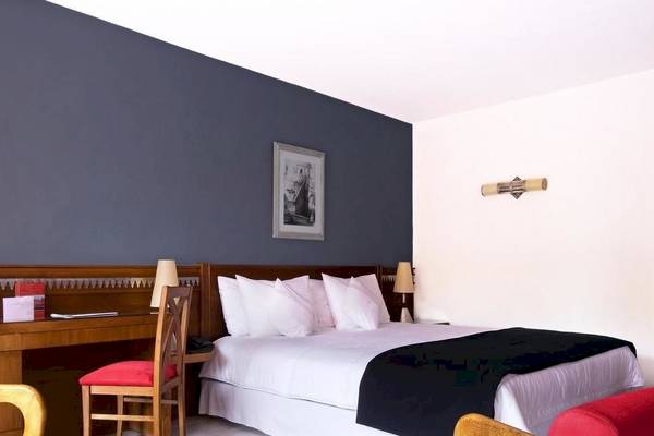 Le Meridien N'Fis Hotelzimmer mit Bett, Schreibtisch und Stühlen.