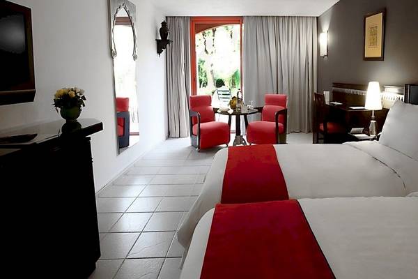Hotelzimmer von Le Meridien N'Fis mit zwei Betten, roten Sesseln und Tisch