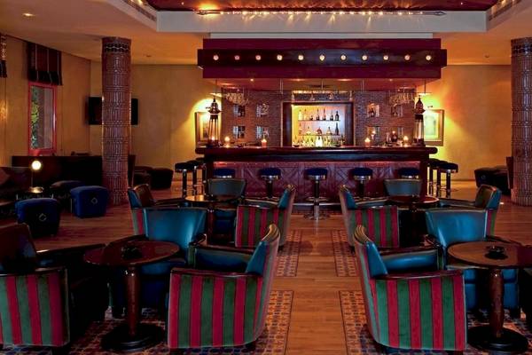 Innenansicht der Bar im Le Meridien N'Fis Hotel mit blauen und roten Stühlen und Tischen.