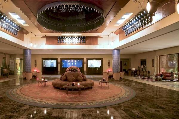 Empfangsbereich des Le Meridien N'Fis Hotels mit zentralem Blumenarrangement und runden Couchtische.