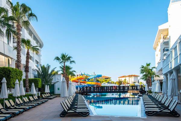 Außenbereich des Alba Queen Hotels mit Pool, Wasserrutschen und Sonnenschirmen.