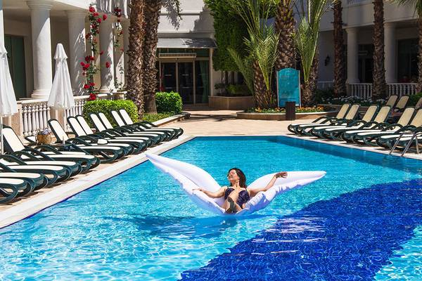 Frau auf einem großen weißen Schwimmtier im Pool des Alba Queen Hotels