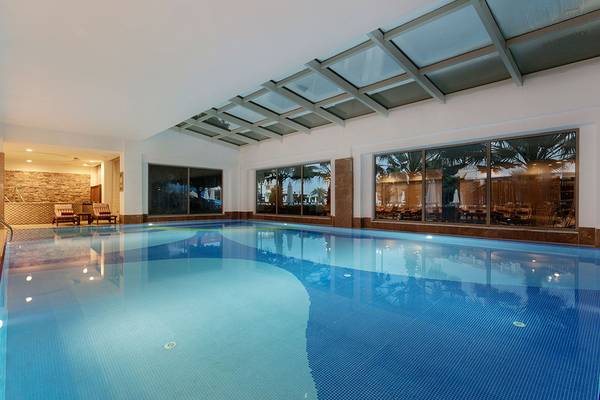 Innenpool des Alba Queen Hotels mit hellem Wasser und Glaswänden.