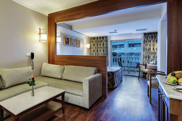 Innenansicht eines Zimmers im Alba Queen Hotel mit Sofa, Tisch, Balkon und Bett