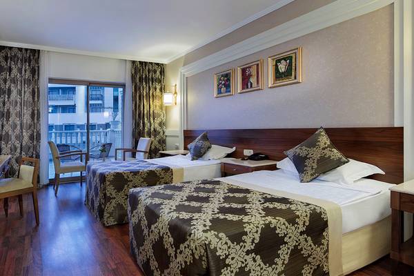 Hotelzimmer des Alba Queen Hotels mit zwei Betten, einem Balkon und Blick auf ein anderes Gebäude.