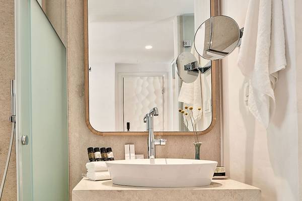 Badezimmer im Myconian Kyma Hotel mit Dusche, Waschbecken und Spiegel.