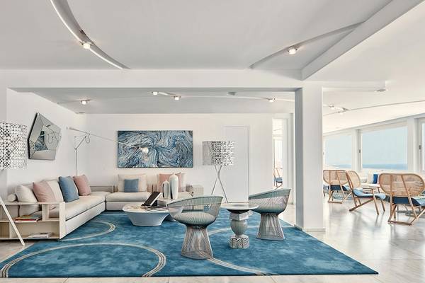 Innenbereich des Myconian Kyma Hotels mit weißem Sofa, blauem Teppich und modernen Möbeln.