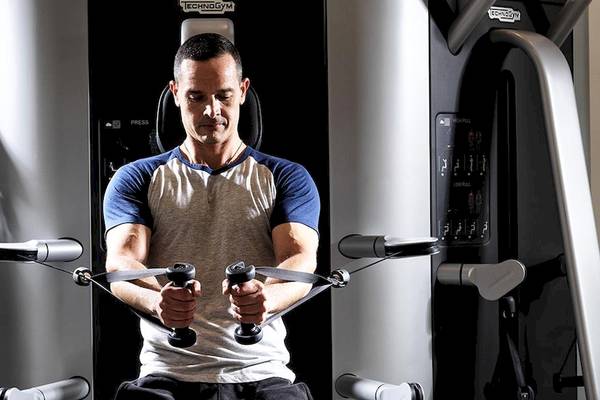 Mann im Fitnessstudio, der an einem Kabelzuggerät trainiert