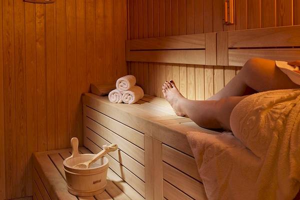 Person in einer Holzsauna des Myconian Kyma Hotels mit Handtuch und Holzeimer