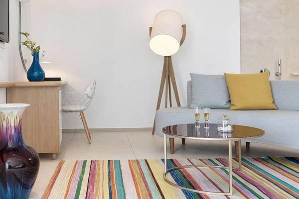 Inneneinrichtung des Myconian Kyma Hotelzimmers mit Schreibtisch, Stuhl, Fernseher, Lampe, Couch und Tisch.