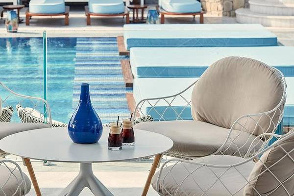 Außenbereich des Myconian Kyma Hotels mit mehreren Sesseln und einem Pool im Hintergrund.