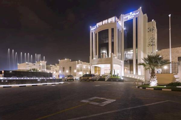 Nachtansicht des Belad Bont Resorts mit einem Brunnen und beleuchteten Gebäuden.
