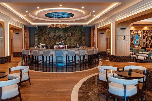 Innenansicht der Bar im Regnum Carya Golf & Spa Resort mit runden Tischen und Stühlen.