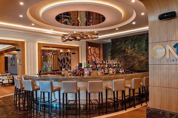 Lobby Bar im Regnum Carya Golf & Spa Resort mit Bartheken, Stühlen und Dekor.