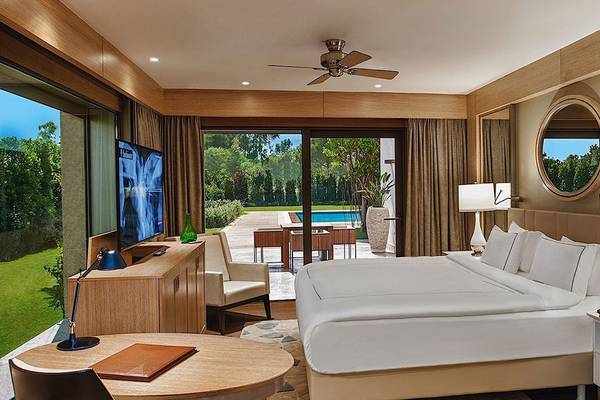 Suite-Zimmer im Regnum Carya Golf & Spa Resort mit Blick auf den Pool und Garten.