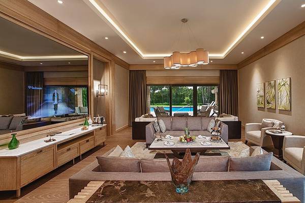 Wohnzimmer des Regnum Carya Golf & Spa Resorts mit Swimmingpool im Hintergrund.