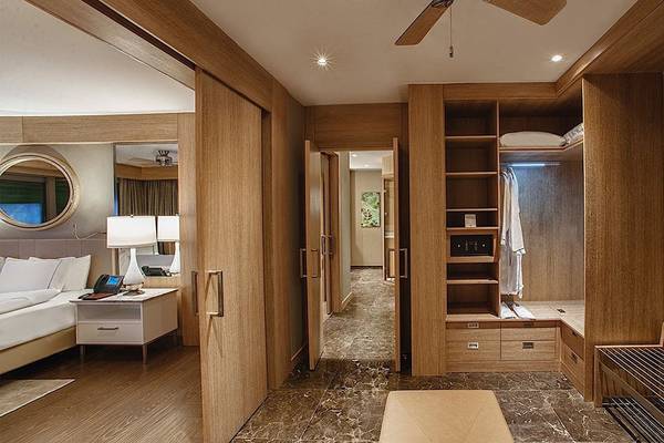 Ein Schlafzimmer im Regnum Carya Golf & Spa Resort mit einem offenen Kleiderschrank und einer Kommode neben dem Bett.