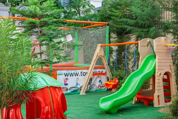 Kinderspielplatz im Freien im Well Palace Side Hotel mit Rutsche und Schaukeln.