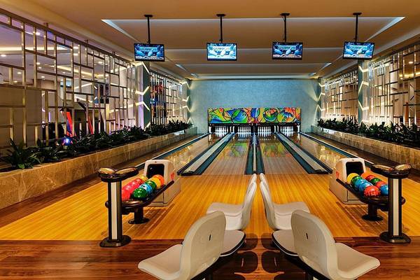 Innenansicht der Bowlingbahn im Regnum Carya Golf & Spa Resort mit bunten Wänden und Fernsehern an der Decke.