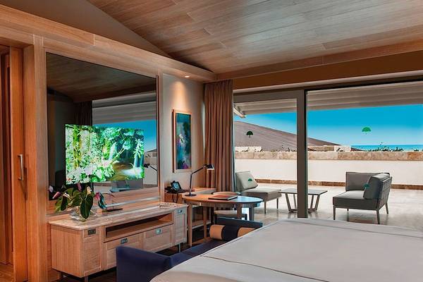 Innenansicht einer Suite im Regnum Carya Golf & Spa Resort mit großem Fernseher, Möbeln und Meerblick.