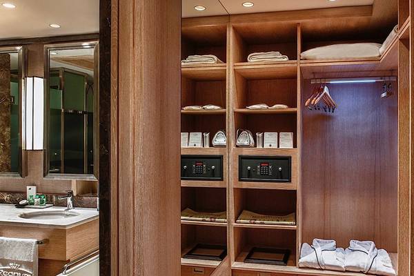 Innenansicht eines Kleiderschranks im Regnum Carya Golf & Spa Resort mit Regalen, Safe und Accessoires.