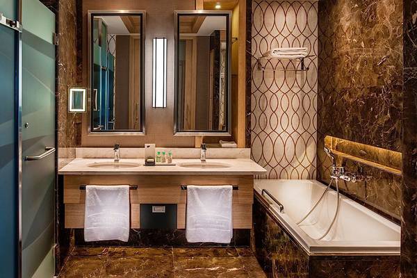 Das Badezimmer des Regnum Carya Golf & Spa Resorts mit zwei Waschbecken, Spiegeln und Badewanne.