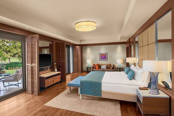Ein elegant eingerichtetes Schlafzimmer im Regnum Carya Golf & Spa Resort mit Blick auf den Golfplatz.