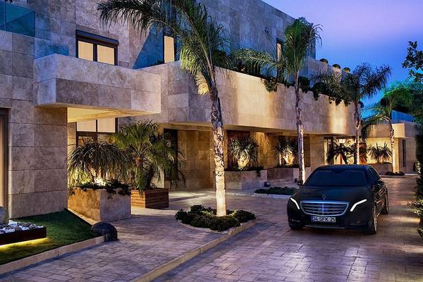 Eingang des Regnum Carya Golf & Spa Resorts mit einem schwarzen Auto und Palmen bei Nacht