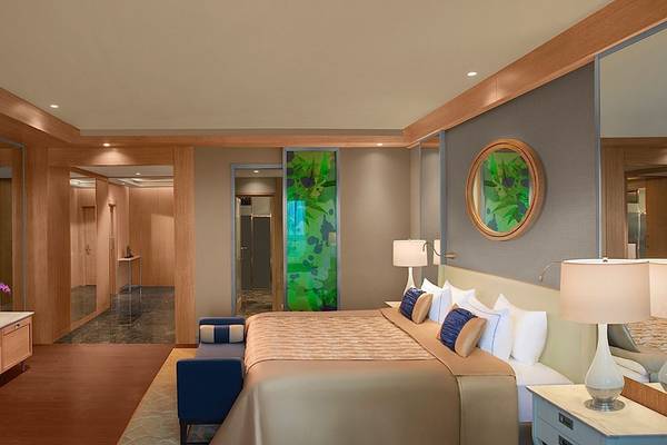 Schlafzimmer im Regnum Carya Golf & Spa Resort mit Fernseher, Bett, Nachttischen und Lampen.