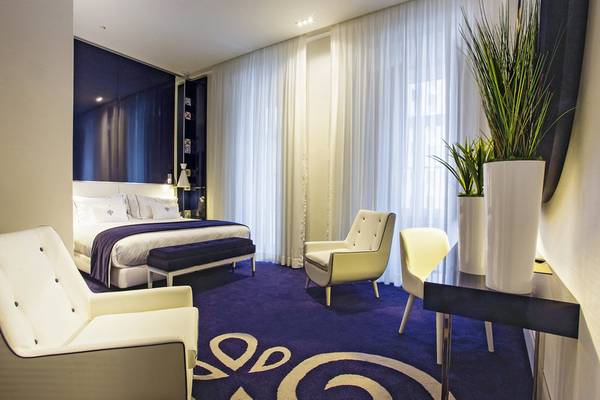 Schlafzimmer im Portugal Boutique Hotel mit Doppelbett, Stühlen und Pflanzen.