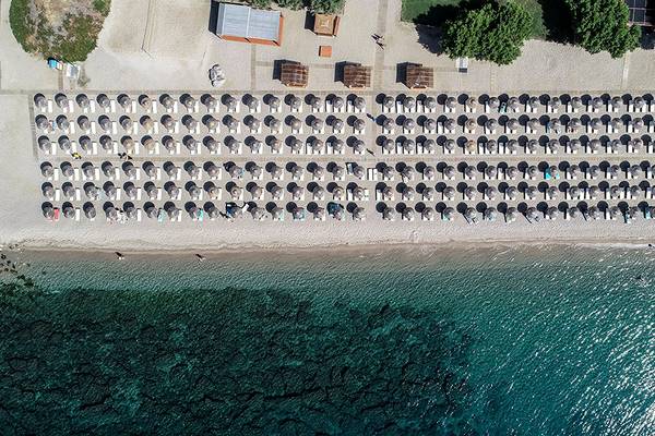 Luftaufnahme des Mitsis Blue Domes Resorts mit vielen Sonnenliegen am Strand