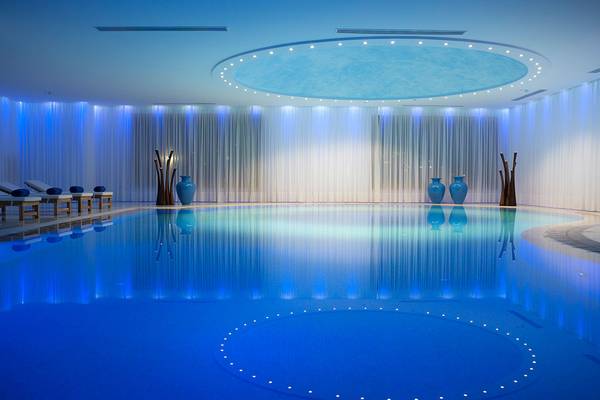 Innenpool im Mitsis Blue Domes Resort & Spa mit blauen Lichtern und Vasen.